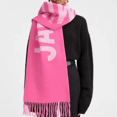 Rosa Schal mit großem Buchstabenprint, getragen über schwarzem Pullover