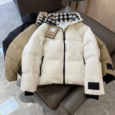 Cremeweiße Daunenjacke mit dunklem Karokragen über einem Stuhl